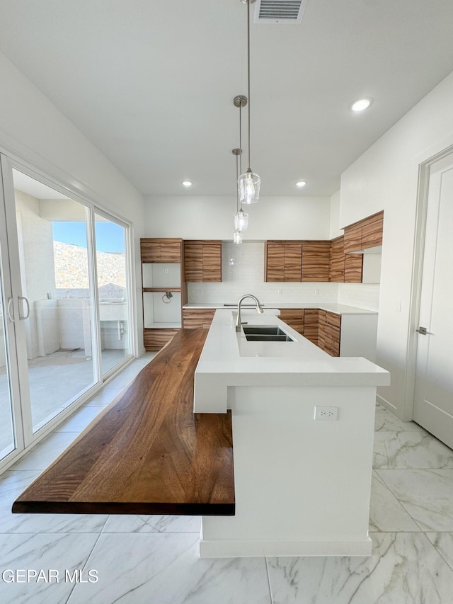 1783 Urijah Pl, El Paso, TX 79928 - kitchen with brown cabinets, modern cabinets, a sink, light marble finish flooring, and light countertops