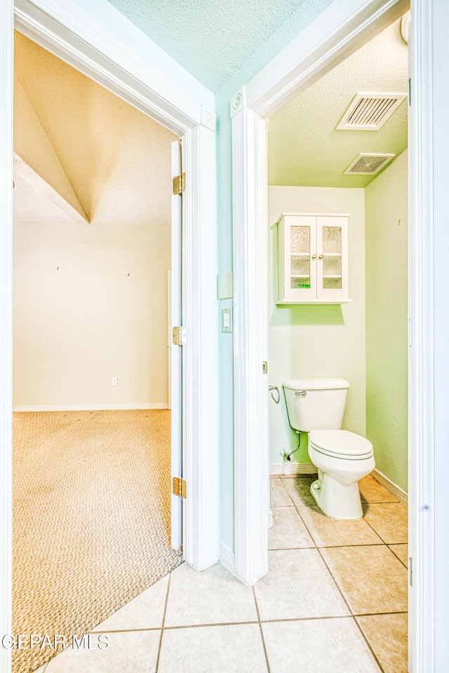 bathroom featuring toilet, a textured ceiling, and tile patterned floors