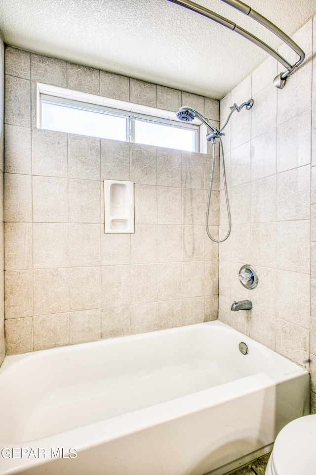 bathroom featuring toilet, a healthy amount of sunlight, tiled shower / bath combo, and a textured ceiling