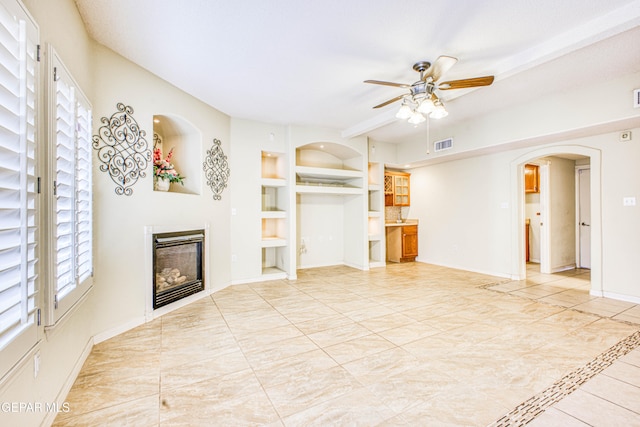 unfurnished living room featuring ceiling fan and built in features