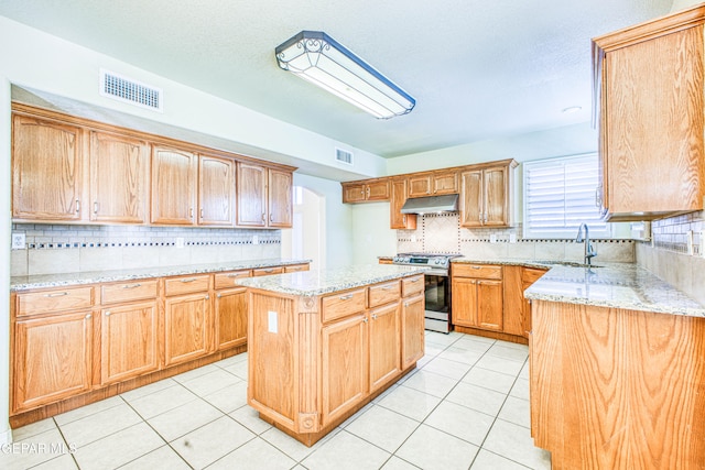 kitchen featuring sink, light tile patterned flooring, a kitchen island, backsplash, and stainless steel range oven