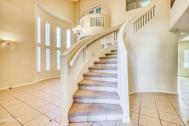 stairway with tile patterned floors, a chandelier, and a towering ceiling