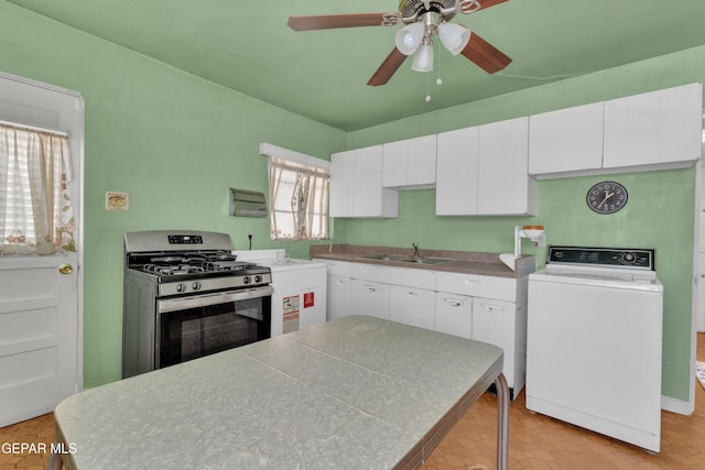 kitchen featuring washer / dryer, stainless steel gas stove, white cabinetry, and plenty of natural light