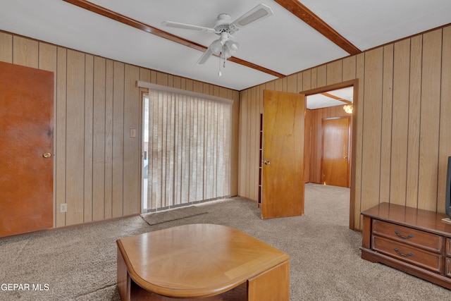 living area with ceiling fan, wood walls, and light colored carpet