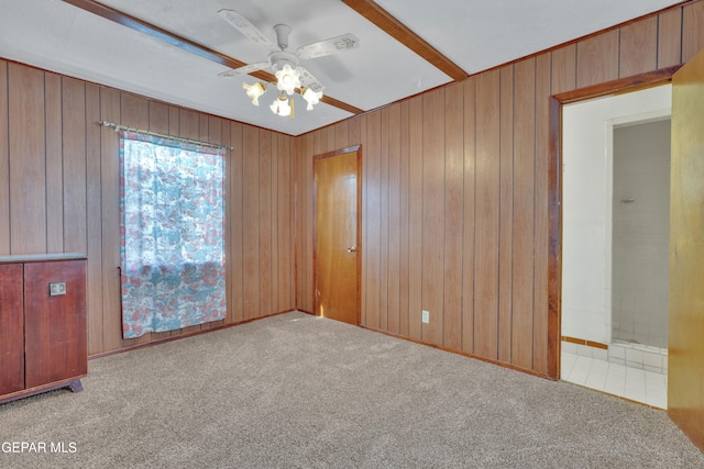 spare room featuring light carpet, wooden walls, and ceiling fan