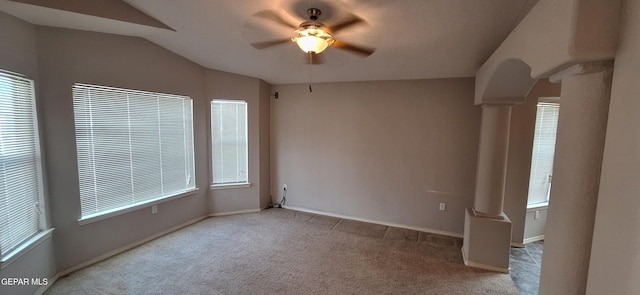 unfurnished room featuring ornate columns, lofted ceiling, ceiling fan, and light carpet