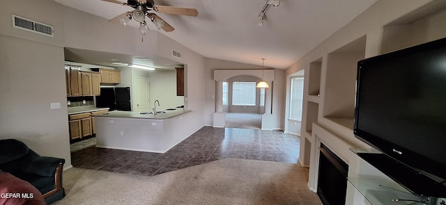 kitchen featuring black fridge, kitchen peninsula, ceiling fan, decorative light fixtures, and vaulted ceiling