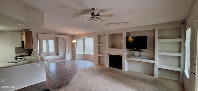 unfurnished living room featuring lofted ceiling, tile patterned floors, sink, ceiling fan, and built in features