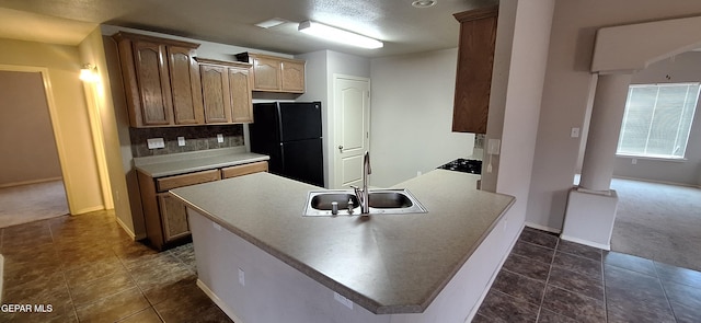 kitchen with decorative backsplash, black fridge, sink, and dark carpet