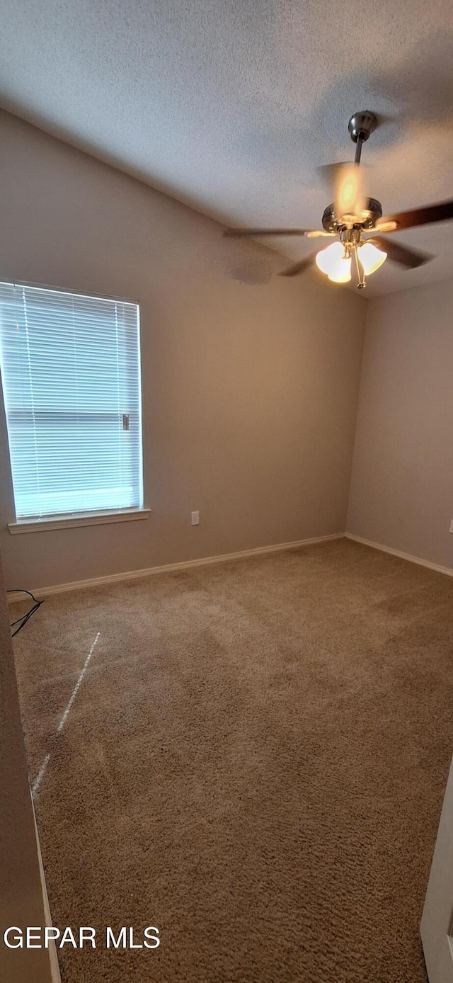 carpeted spare room featuring a textured ceiling and ceiling fan