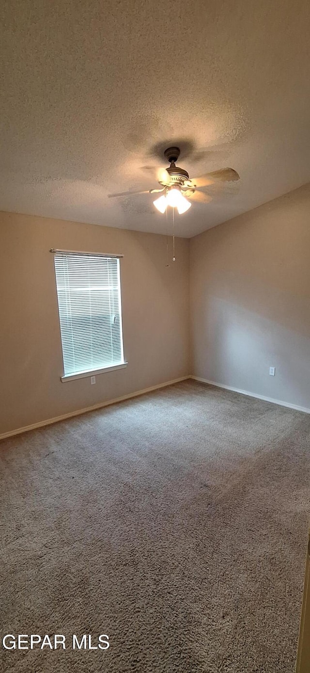 carpeted empty room with ceiling fan and a textured ceiling