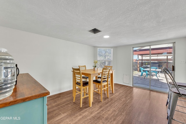 dining area with dark wood-type flooring and a textured ceiling