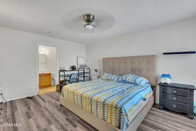 bedroom with a textured ceiling, ensuite bath, hardwood / wood-style flooring, and ceiling fan