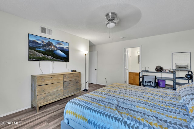 bedroom with a textured ceiling, dark hardwood / wood-style flooring, ceiling fan, and connected bathroom