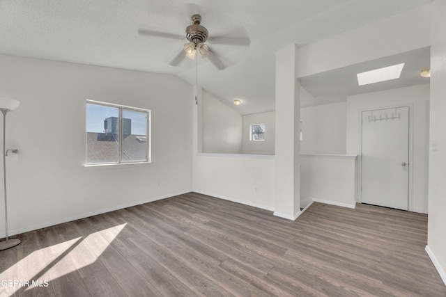 spare room featuring lofted ceiling with skylight, wood-type flooring, ceiling fan, and a textured ceiling