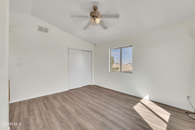 empty room with lofted ceiling, wood-type flooring, and ceiling fan