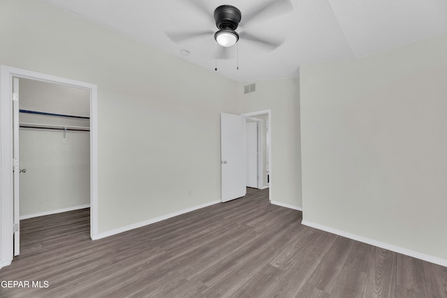 unfurnished bedroom featuring dark hardwood / wood-style flooring, ceiling fan, a spacious closet, and a closet