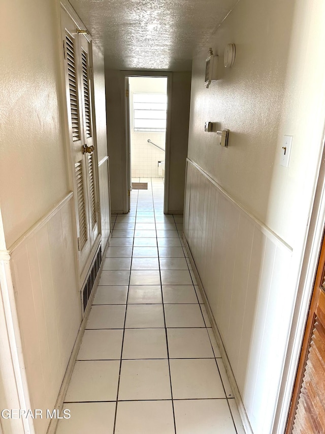 corridor featuring a textured ceiling and light tile patterned floors