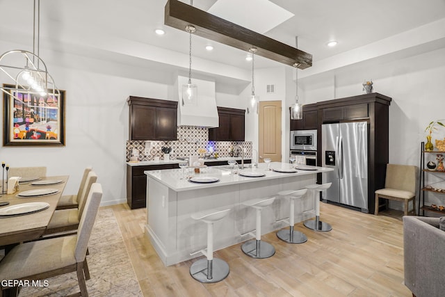 2300 Tierra Zaria, El Paso, TX 79938 - kitchen featuring appliances with stainless steel finishes, dark brown cabinetry, tasteful backsplash, light wood-style floors, and light countertops