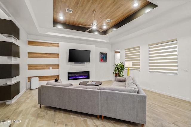 2300 Tierra Zaria, El Paso, TX 79938 - living room featuring a tray ceiling, ceiling fan, a glass covered fireplace, wood ceiling, and light wood-style floors