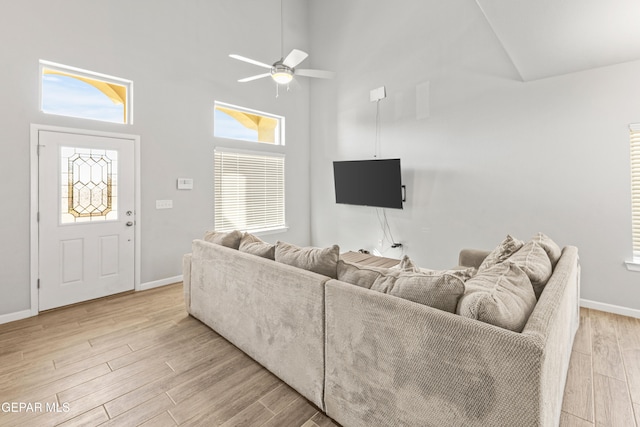 living room featuring light wood-type flooring, a high ceiling, and plenty of natural light