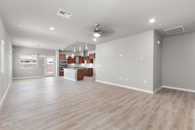 unfurnished living room with sink, light wood-type flooring, and ceiling fan with notable chandelier