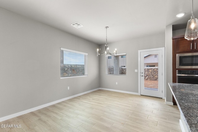 unfurnished dining area featuring a chandelier and light hardwood / wood-style floors