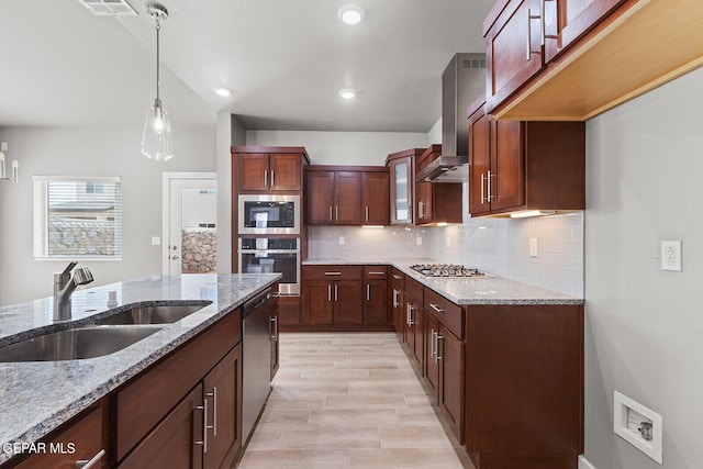 kitchen featuring appliances with stainless steel finishes, sink, hanging light fixtures, light stone counters, and decorative backsplash