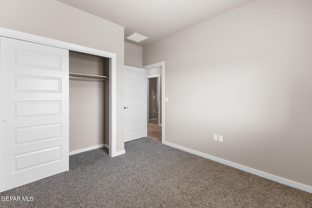 unfurnished bedroom with dark colored carpet and a closet