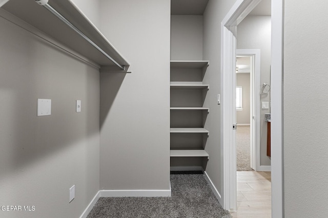 spacious closet with dark colored carpet