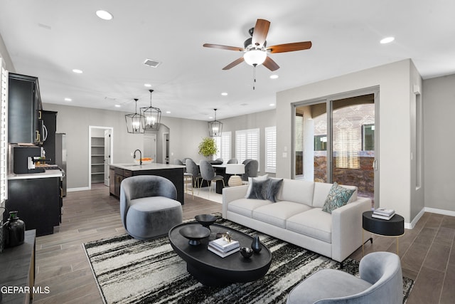 living room with sink, ceiling fan with notable chandelier, and dark hardwood / wood-style flooring