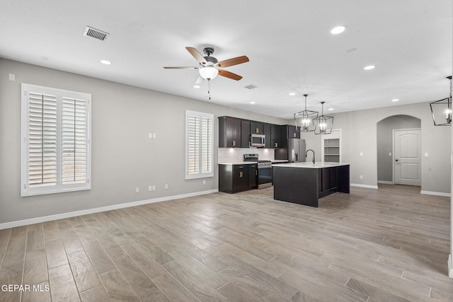 kitchen featuring a healthy amount of sunlight, appliances with stainless steel finishes, decorative light fixtures, and a center island with sink