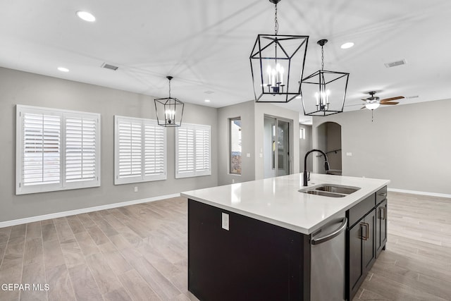 kitchen featuring light hardwood / wood-style flooring, sink, hanging light fixtures, and an island with sink