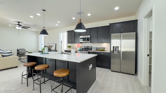 5844 Kobe Bryant St, El Paso, TX 79924 - kitchen featuring appliances with stainless steel finishes, a kitchen bar, an island with sink, light countertops, and light wood-style floors