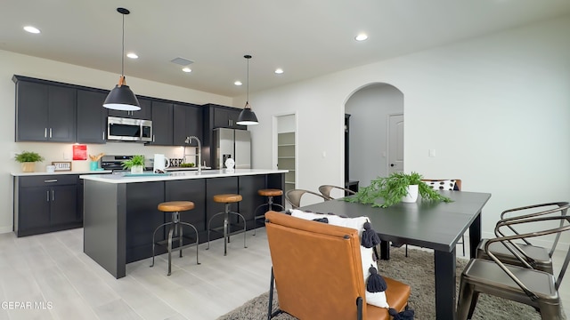 5844 Kobe Bryant St, El Paso, TX 79924 - kitchen with appliances with stainless steel finishes, arched walkways, a breakfast bar area, light countertops, and recessed lighting