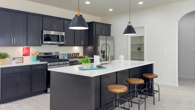 5844 Kobe Bryant St, El Paso, TX 79924 - kitchen featuring stainless steel appliances, arched walkways, a center island with sink, a kitchen bar, and light countertops