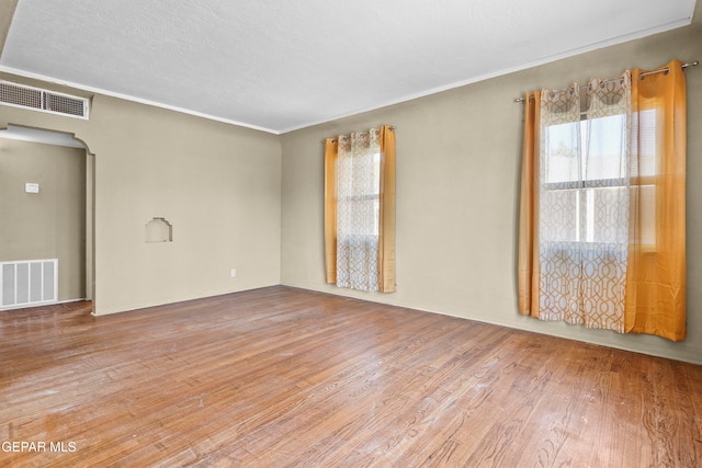 spare room with ornamental molding, a textured ceiling, and hardwood / wood-style flooring