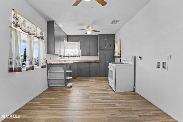 kitchen featuring ceiling fan, light hardwood / wood-style flooring, gas range gas stove, gray cabinets, and sink