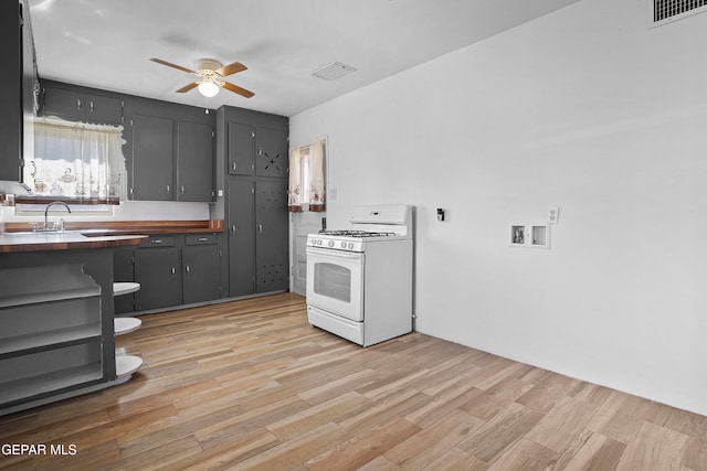 kitchen with ceiling fan, light hardwood / wood-style flooring, butcher block counters, sink, and white gas range oven