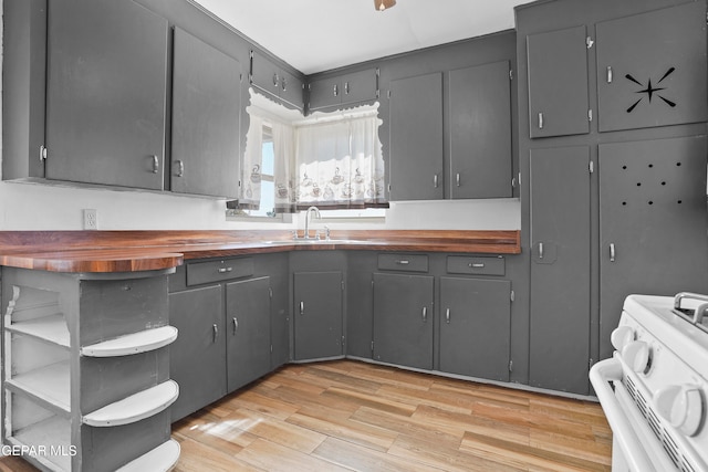 kitchen featuring stove, butcher block counters, light hardwood / wood-style flooring, and gray cabinetry