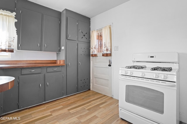 kitchen featuring gray cabinets, butcher block counters, gas range gas stove, and light wood-type flooring