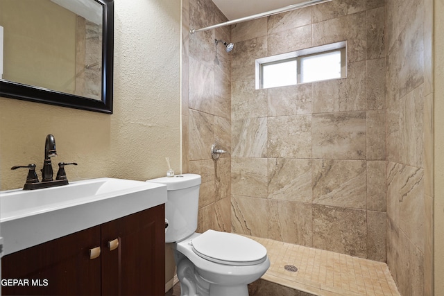 bathroom with vanity, toilet, and tiled shower