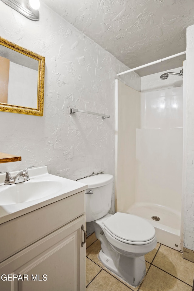 bathroom with vanity, toilet, a shower, and tile patterned flooring