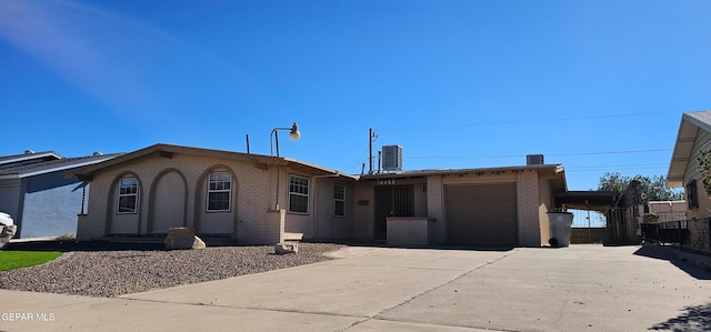 ranch-style house with brick siding, a chimney, central AC, a garage, and driveway