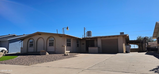 ranch-style home featuring brick siding, concrete driveway, entry steps, a garage, and cooling unit