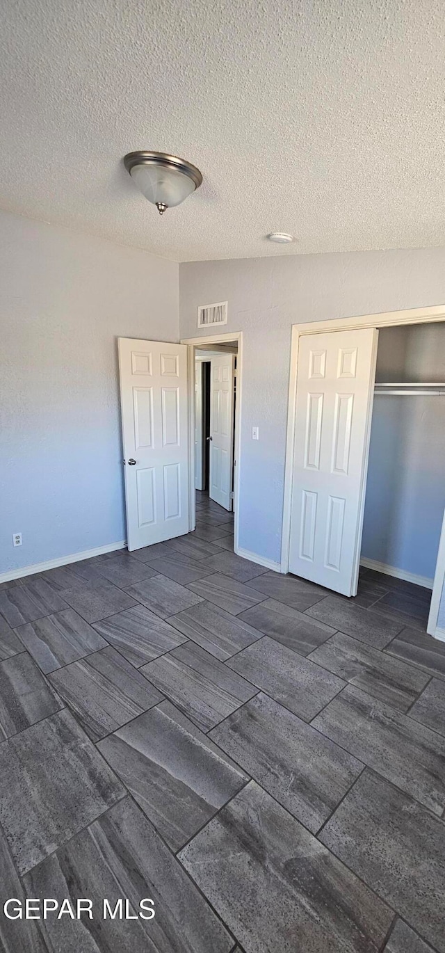 unfurnished bedroom with a textured ceiling and a closet