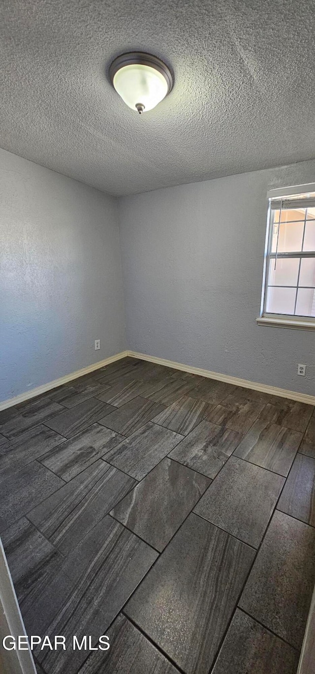 empty room with dark wood-type flooring and a textured ceiling