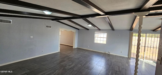 unfurnished room with lofted ceiling with beams and a textured ceiling