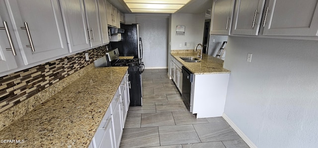 kitchen featuring decorative backsplash, light stone counters, extractor fan, black appliances, and sink