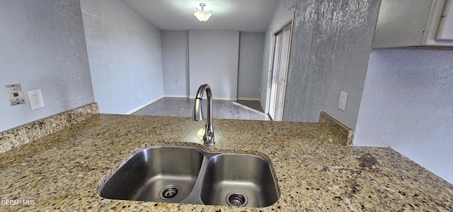 kitchen featuring light stone counters and sink